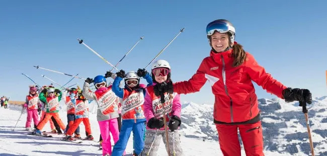 Lernende Skifahrer in Skikurs mit Trainerin im Schnee