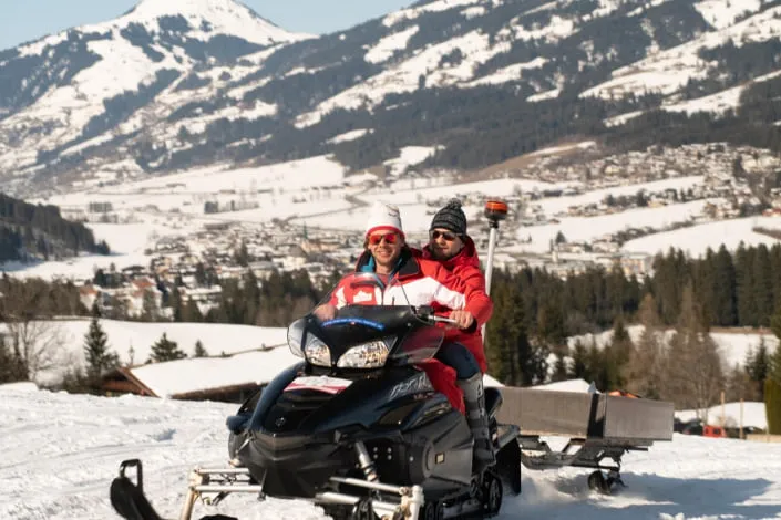 Two people on a snowmobile in Kirchberg.