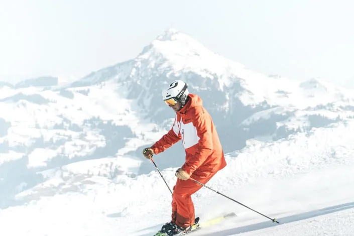 Skier on slope in Kirchberg, snow-covered mountains