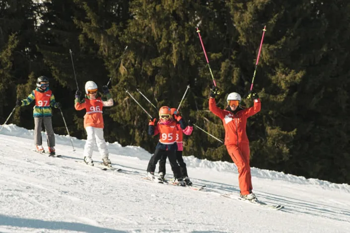 Skiing kids with instructor on snowy slope